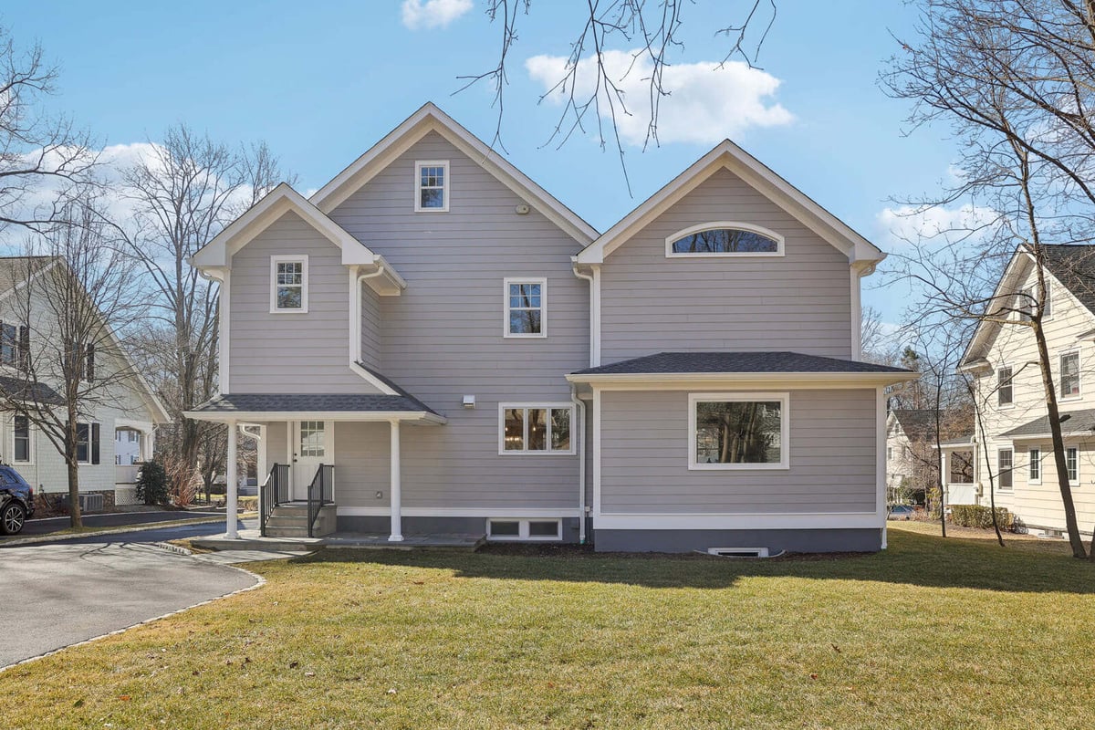 Rear exterior of home in Ridgewood, NJ with gray siding and lawn