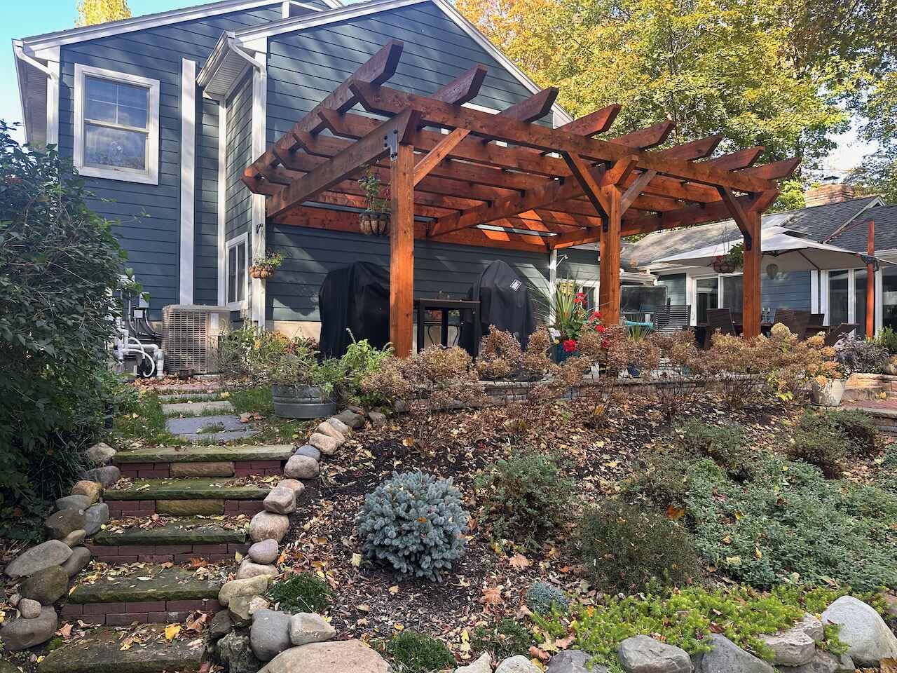 Rustic stone staircase leading to a wooden pergola in Ridgewood, NJ by Fairmount Heights Homes.