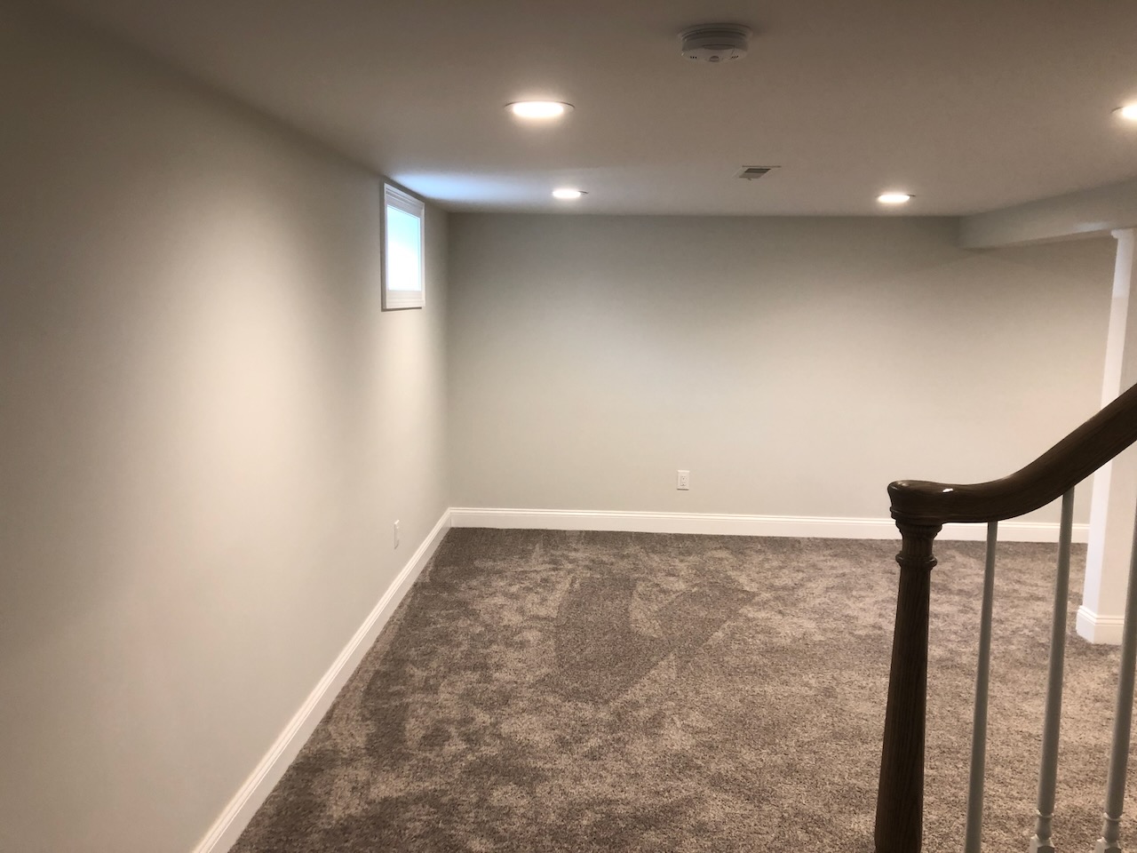 Carpeted basement living area with recessed lighting in Ridgewood home by Fairmount Heights Homes.