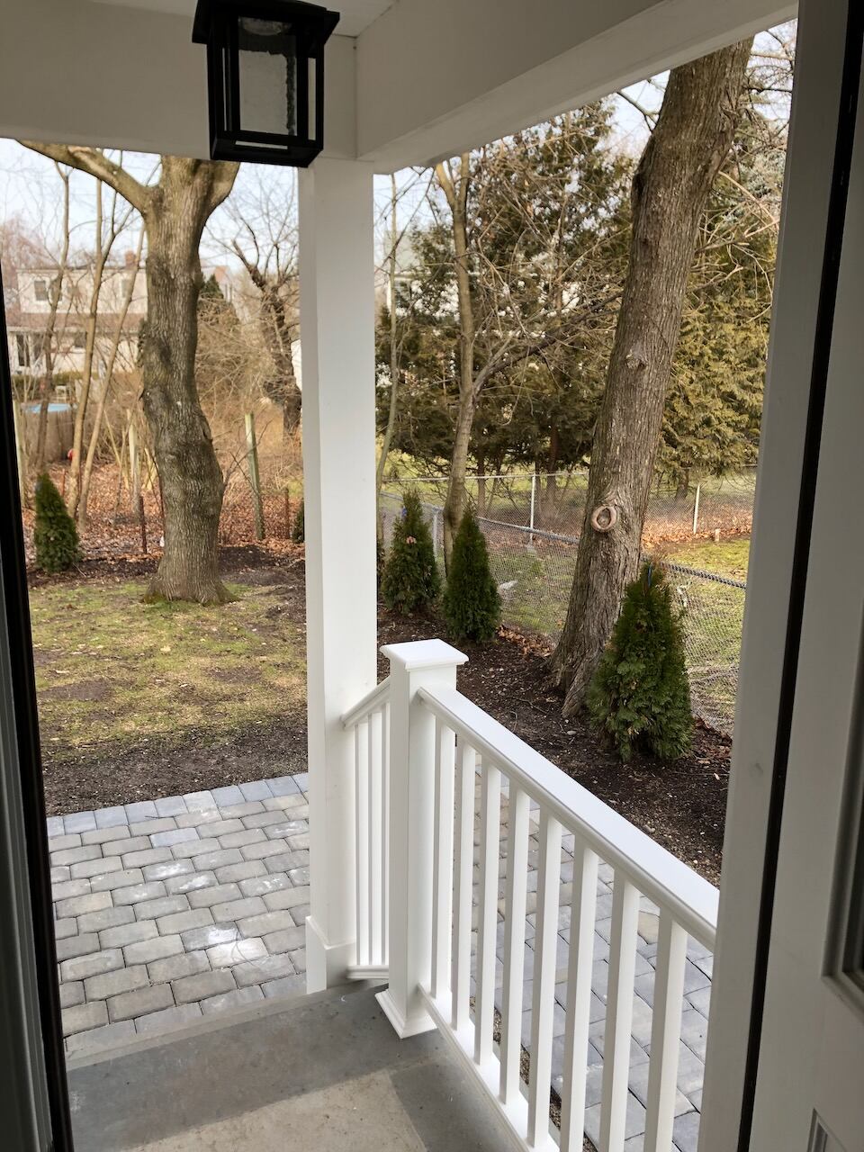 Covered porch with white railing and stone pavers in a Ridgewood, NJ home by Fairmount Heights Homes.