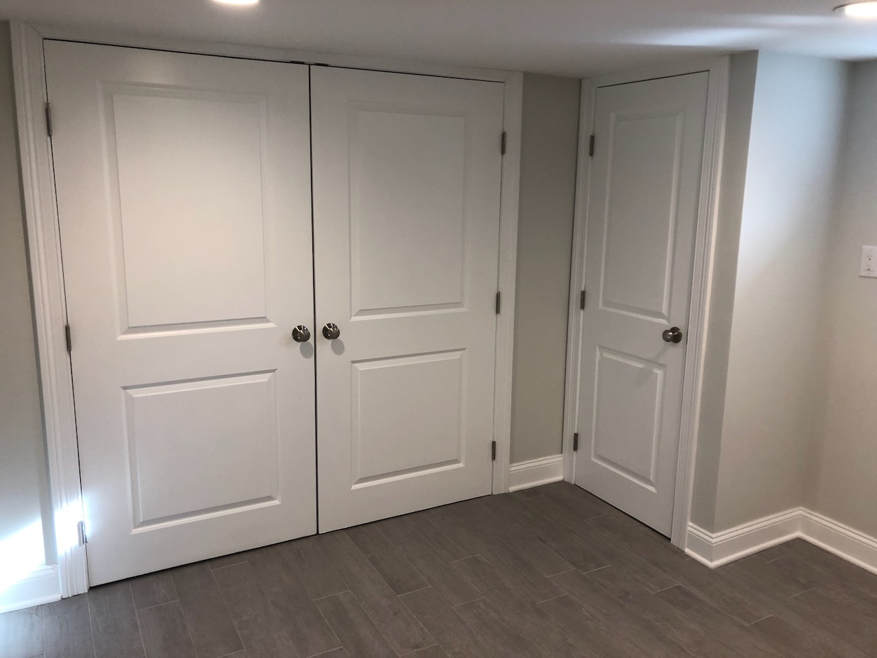 Double closet doors and utility door in finished Ridgewood basement by Fairmount Heights Homes.