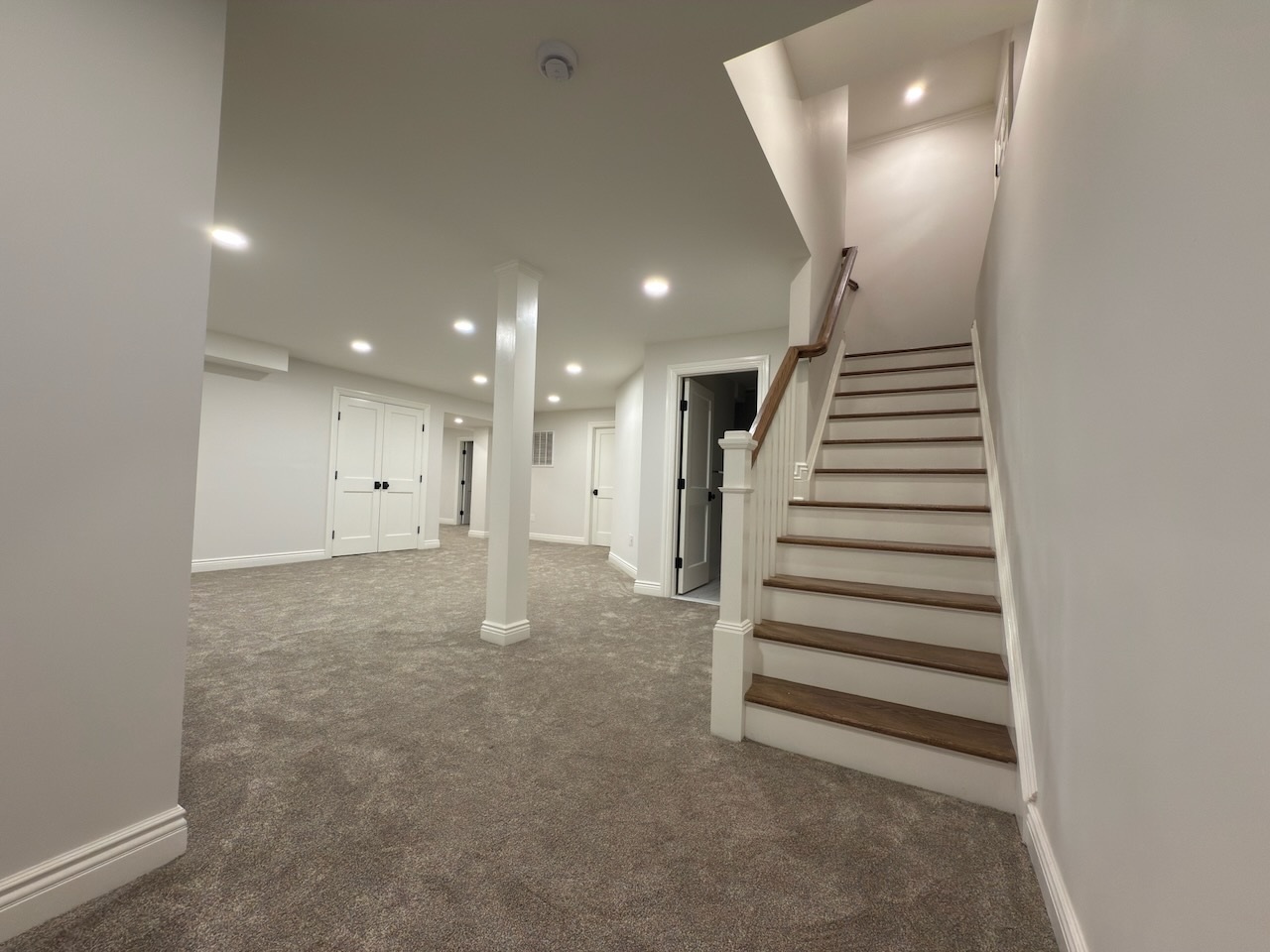 Carpeted basement with stair access and open layout in Ridgewood, NJ custom home by Fairmount Heights Homes