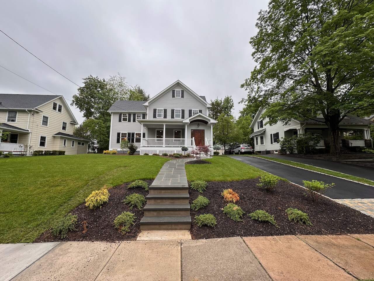 Front exterior of a custom home with landscaped yard and stone walkway in Ridgewood, NJ by Fairmount Heights Homes