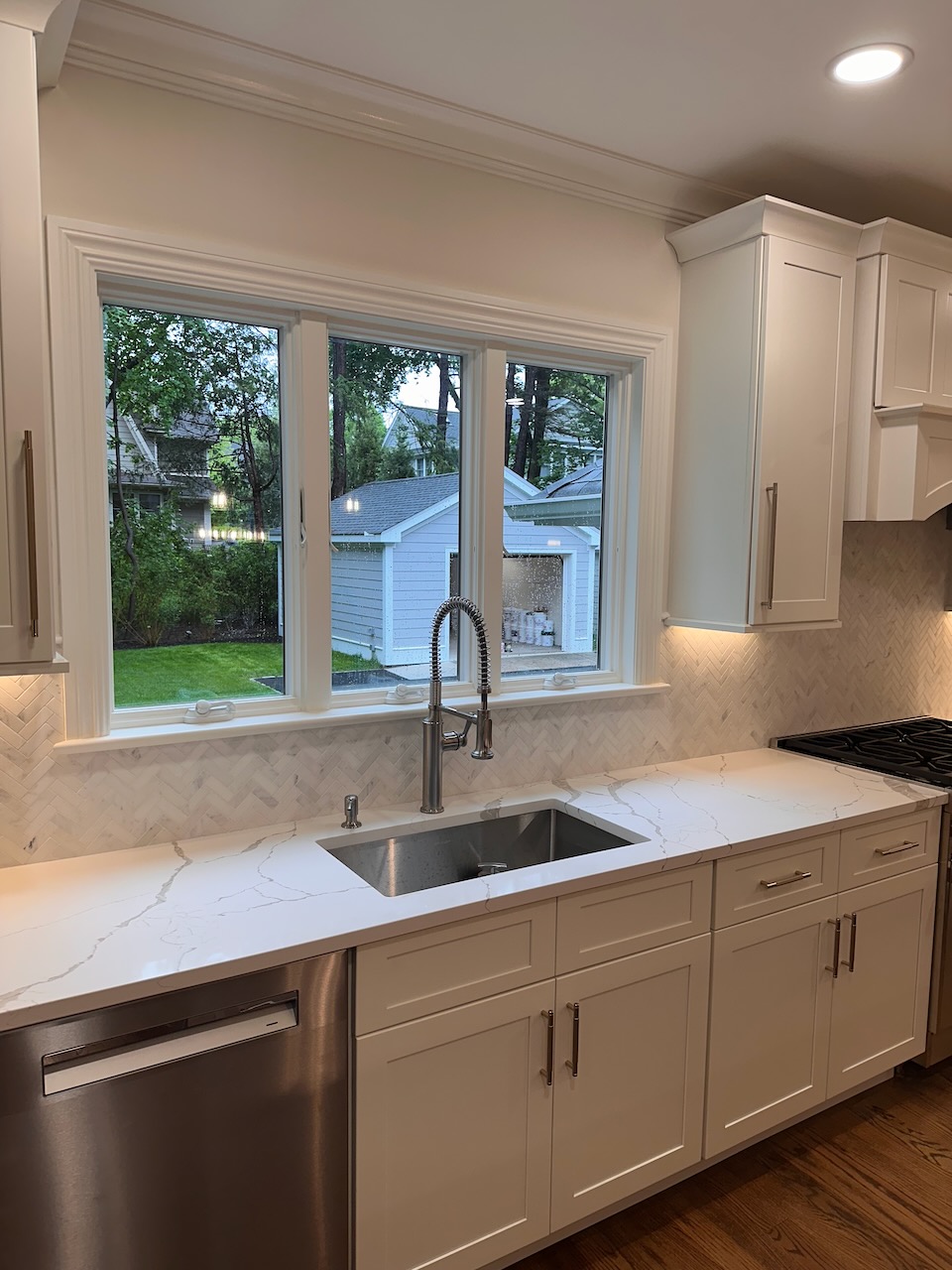 Kitchen sink area with herringbone backsplash and outdoor view in Ridgewood home by Fairmount Heights Homes.