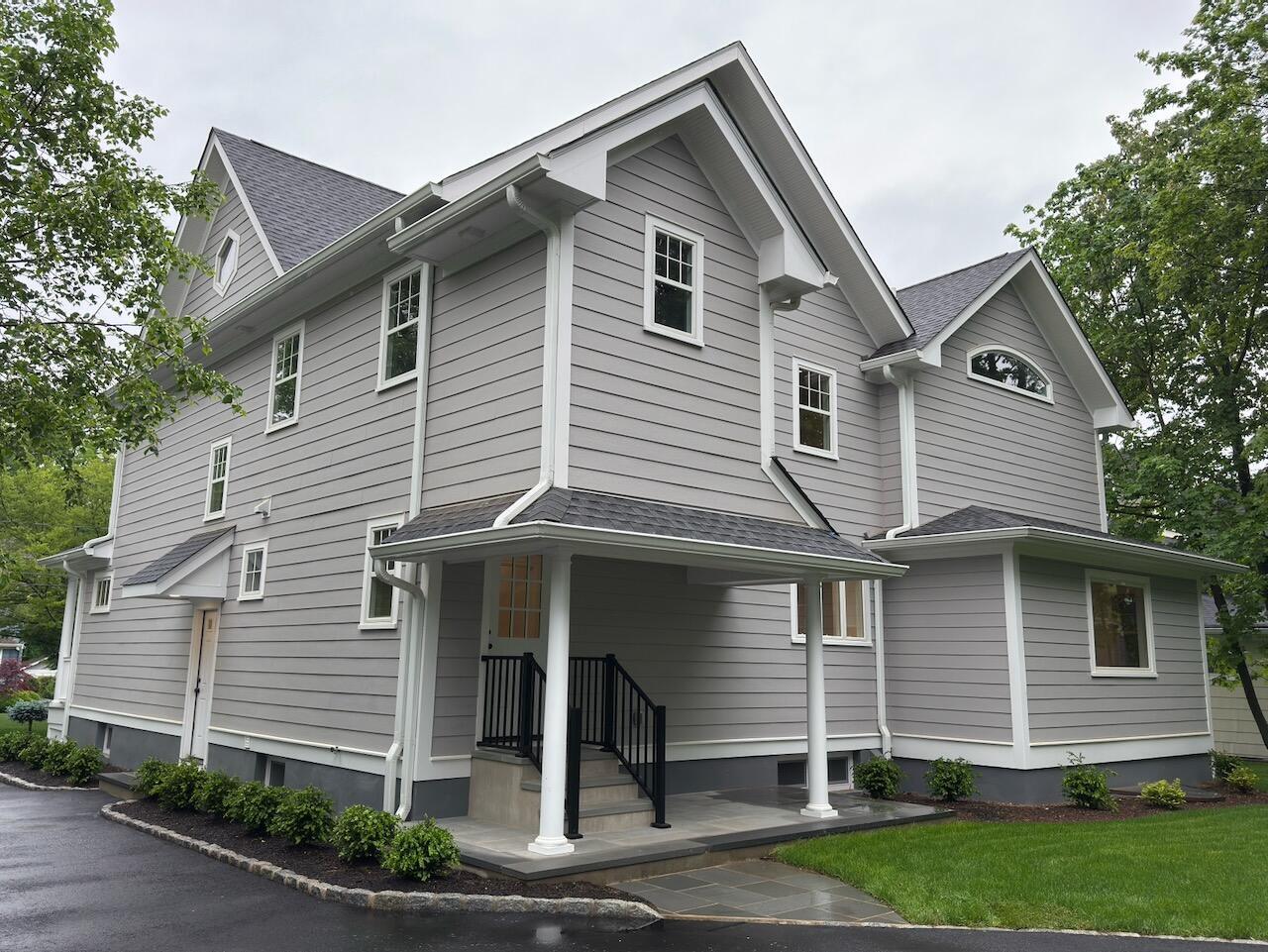 Rear and side view of custom home in Ridgewood, NJ with gabled roof and covered entry by Fairmount Heights Homes