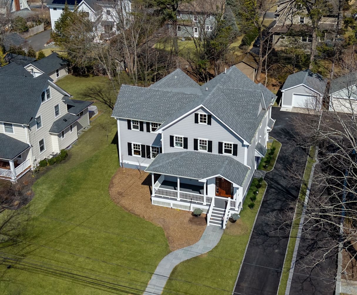 Aerial view of a classic two-story home in Ridgewood, NJ with a front porch and detached garage Aerial view of a classic two-story home in Ridgewood, NJ with a front porch and detached garage
