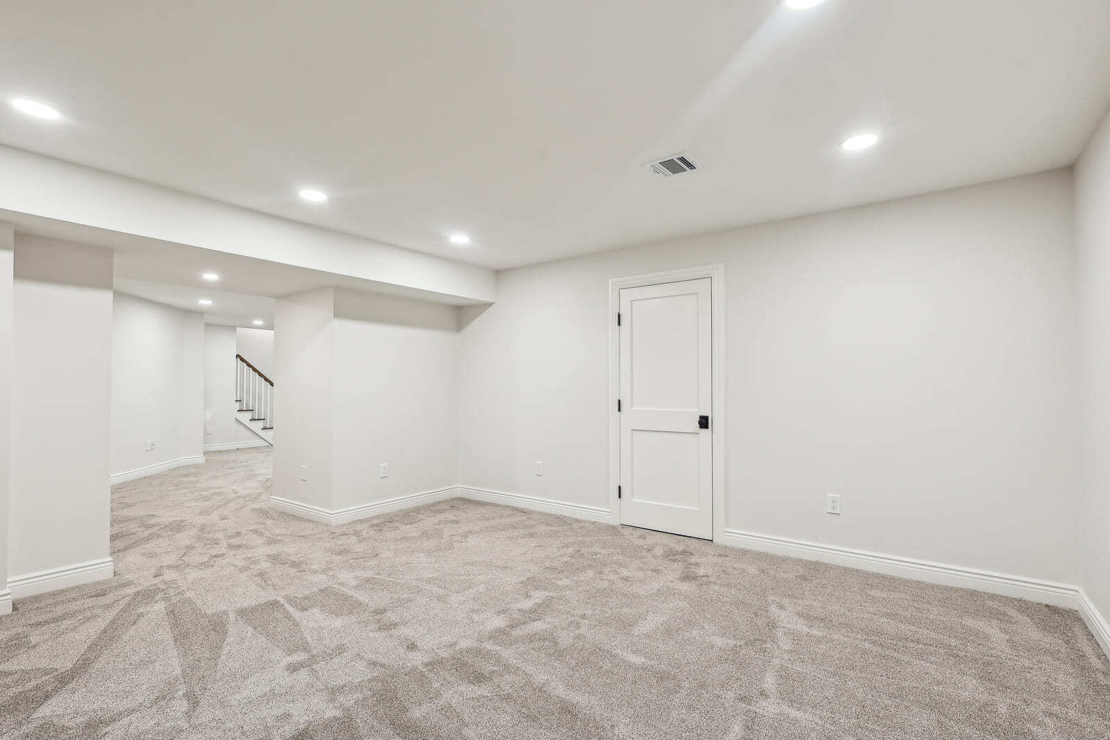 Basement living area in Ridgewood, NJ with plush carpet and support columns